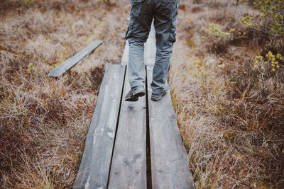 Low section of man walking on boardwalk