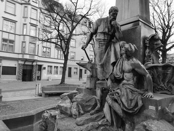 Statue by building against bare tree