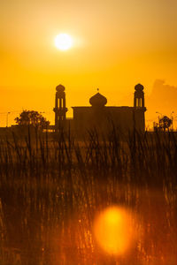 Silhouette built structure against orange sky