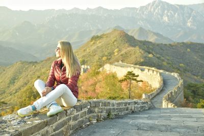 Woman sitting on top of the great wall in the mountains
