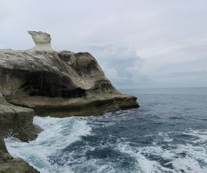 Rock formation in sea against sky