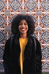 Portrait of smiling young woman standing against tiled wall
