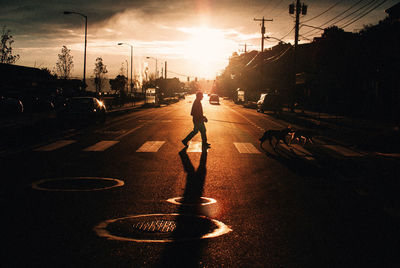 Man riding bicycle on city street during sunset