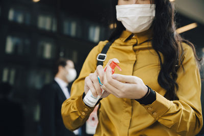 Woman with face mask applying hand gel