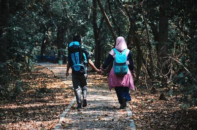 Rear view of women walking on footpath in forest