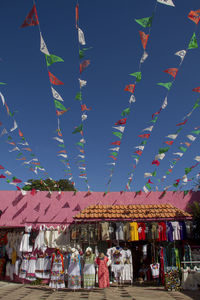 Multi colored flags hanging in market against sky