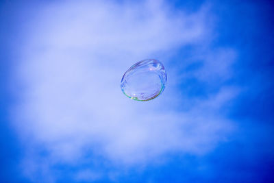 Low angle view of bubbles against blue sky