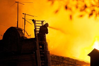 Firefighter spraying water on burning building