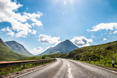 Road leading towards mountains against sky