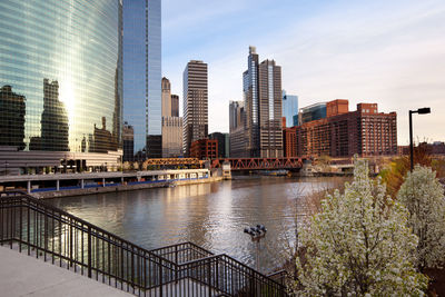 Modern buildings by river against sky in city