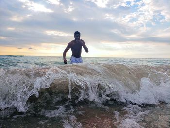 Full length of man on rock at beach against sky