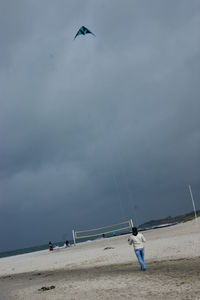 Rear view of man flying kite at beach
