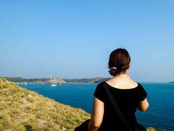 Rear view of woman looking at sea against clear sky