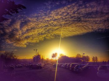 Cars on road against sky during sunset