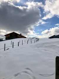 Wooden posts on snow covered land against sky