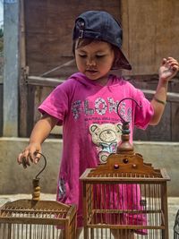  a 5 year old little girl is playing with a birdcage