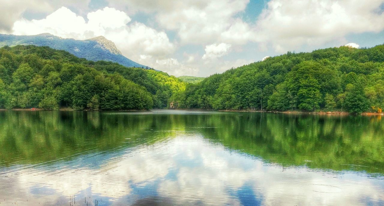 water, tree, tranquil scene, tranquility, lake, reflection, scenics, beauty in nature, sky, mountain, nature, waterfront, cloud - sky, idyllic, green color, cloud, forest, non-urban scene, day, cloudy