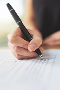 Midsection of woman writing in book