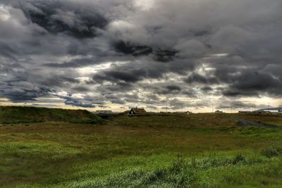 Scenic view of grassy field against cloudy sky