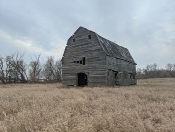 Abandoned house on field against sky