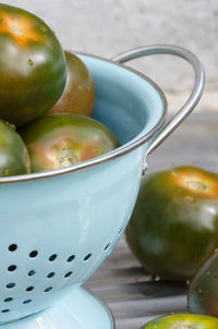 Close-up of unripe tomatoes in colander on table