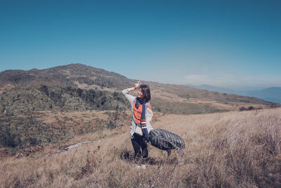 Young woman standing on mountain against clear sky