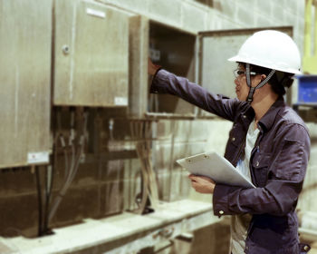 Manual worker wearing hardhat while working in factory