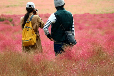 Rear view of couple standing amidst plants on field