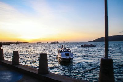 Boats moored in sea at sunset