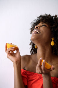 Black woman with afro hair holding cut orange halves smiling