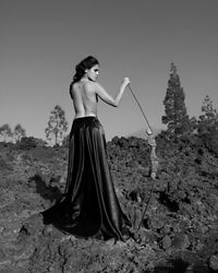 Young woman standing on sand against clear sky