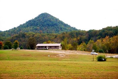 Built structure on grassy field in front of mountains against clear sky