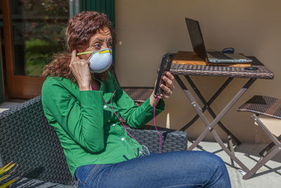 Woman using smart phone sitting on chair at home