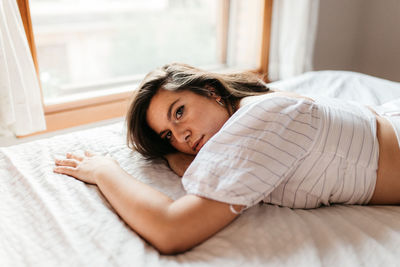 Portrait of woman lying on bed at home