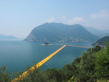 Scenic view of sea by mountains against sky