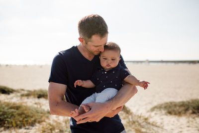 Father cradling infant son on beach