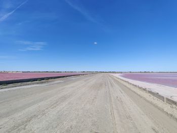 Road passing through land against blue sky