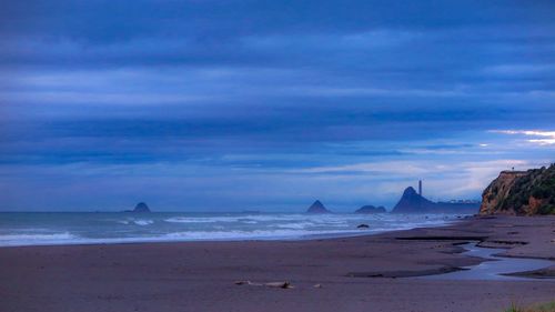 Scenic view of beach against sky at sunset