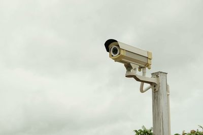 Low angle view of security camera against sky