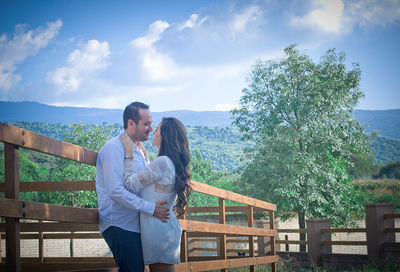 Couple standing by tree against sky