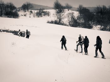 People on snow covered landscape against sky