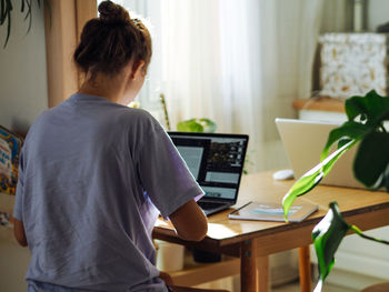 Young pretty woman in homewear working at home, using laptop