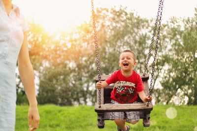 Happy boy holding swing in park