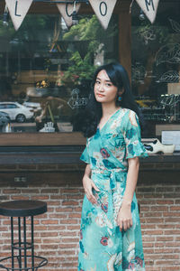 Portrait of a smiling young woman standing against brick wall