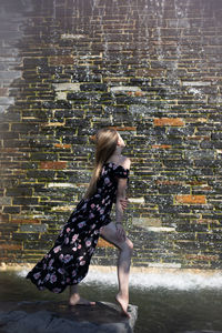Side view of woman against brick wall