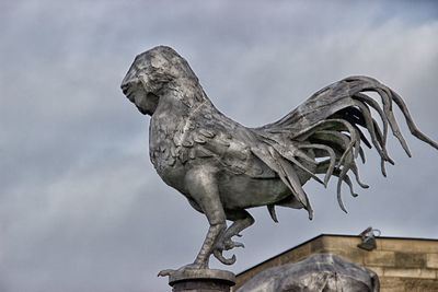 Low angle view of bird statue against sky