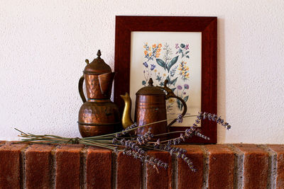 Small pewter jugs with sprigs of lavender placed on the shelf of a brick fireplace.