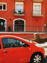 Red car on street by buildings in city