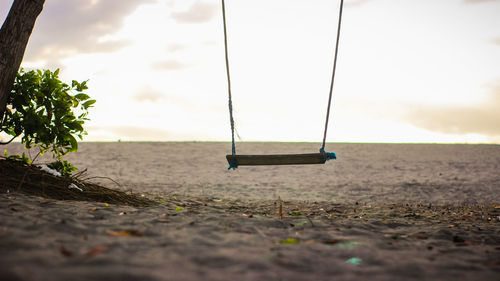 Empty swing at playground against sky