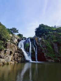 Scenic view of waterfall in forest against sky